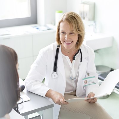 Doctor with medical chart talking with patient in examination room
