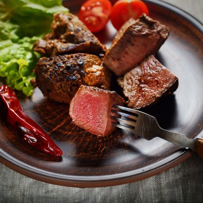 piece of steak on a fork, salad and vegetables