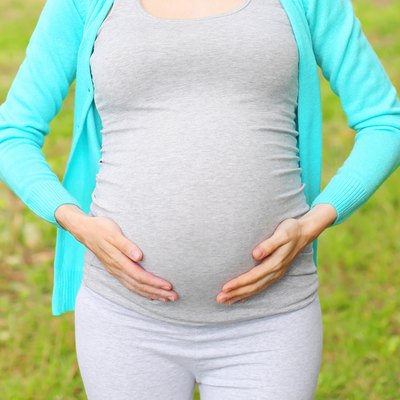 Pregnant young woman outdoors in summer day closeup