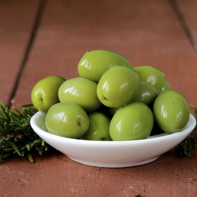 green marinated olives in bowl on a wooden table
