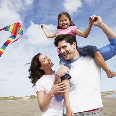 Family Having Fun Flying Kite On Beach Holiday