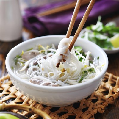 picking up noodles out of a bowl of pho