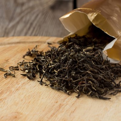 Dry white tea leaves on wooden plate