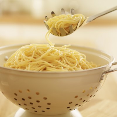Close up of spoon scooping spaghetti in colander