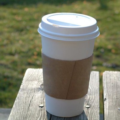 A lone coffee cup on a picnic table.