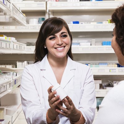 Smiling young pharmacist showing prescription medication to a customer