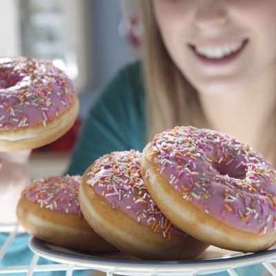 woman taking pink doughnut out of fridge