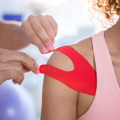 Physiotherapist sticking tape on female patient in clinic