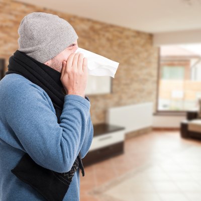 Young man blowing nose into a tissue