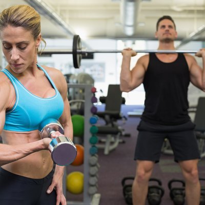 Muscular man and woman lifting weights