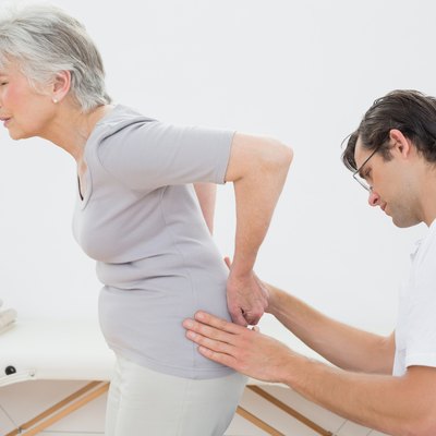 Physiotherapist examining senior woman's back