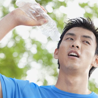 Young Man Drinking Bottled Water in Park