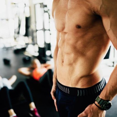 Attractive male torso in gym flexing abs