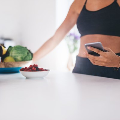Young woman with mobile phone in kitchen