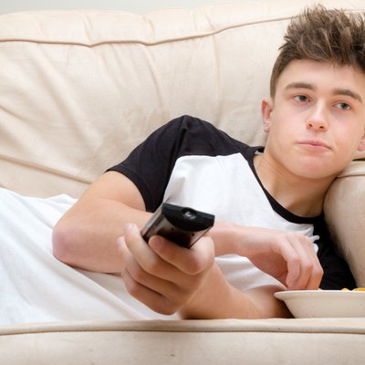 Teenage Boy Laying On A Sofa Watching TV