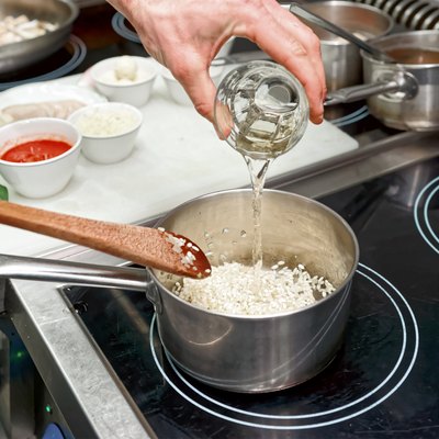 Chef is adding white wine to risotto