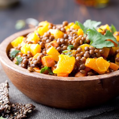 Lentil with carrot and pumpkin ragout in a wooden bowl.