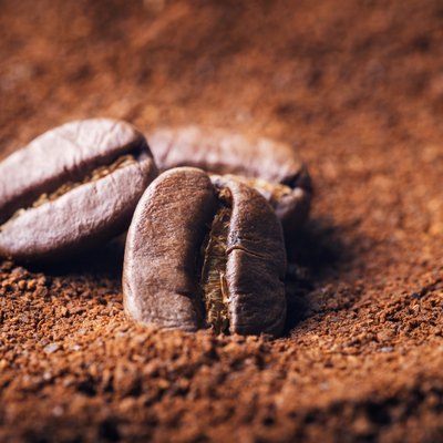 Close up of three beans on ground coffee background