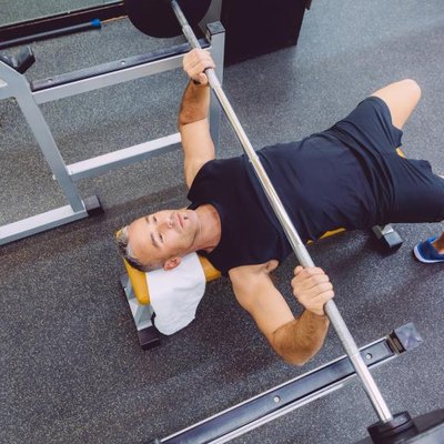 Handsome man doing exercises with barbell on a bench press training in a fitness center