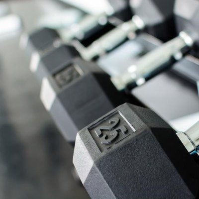 Close up on rows of dumbbells on a rack in a gym.