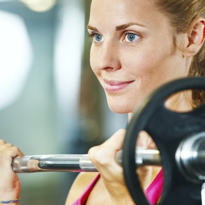 Young woman exercising with barbell in gym.