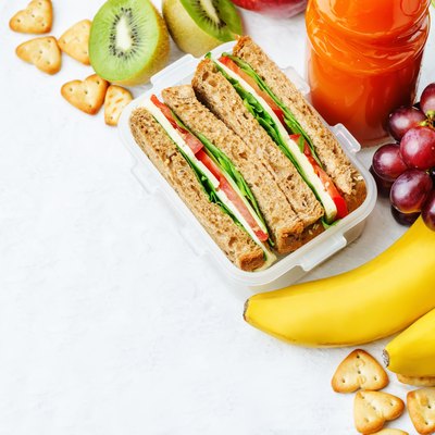 school lunch with a sandwich, fresh fruits, crackers and juice