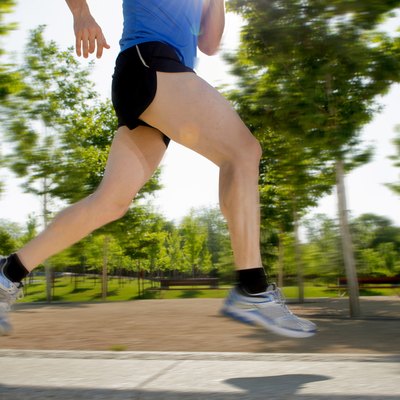 legs of young man running in city park fitness concept