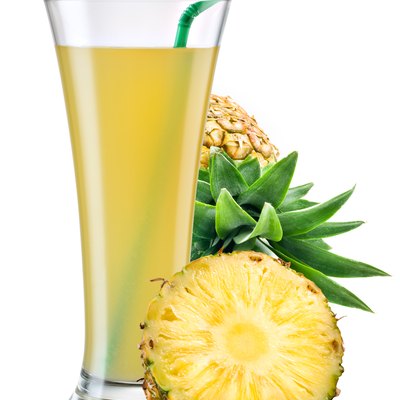 Glass of pineapple juice with fruit isolated on white.