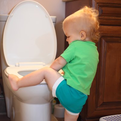 Baby trying to sit on a toilet