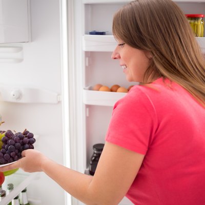 Housewife take plate full of grapes from fridge