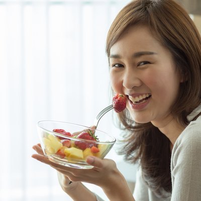 Asian woman is happily eating her fruit salad