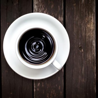 Closeup of black coffee from top view on vintage wood background.