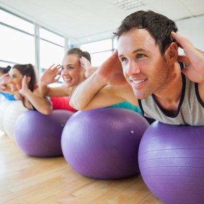Side view of class exercising on fitness balls in a row
