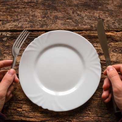 man holding a knife and fork next to the plate