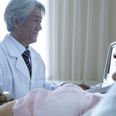 Doctor doing an ultrasound on a pregnant woman lying on her back in the hospital
