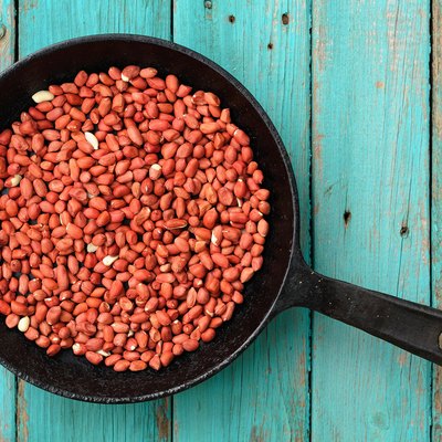 Whole fried pink peanuts in black cast iron pan
