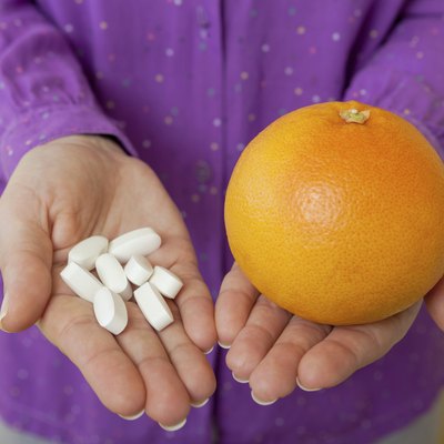 Woman hand with pills medicine tablets and grapefruit