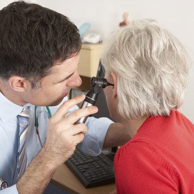 British doctor examining senior woman's ear
