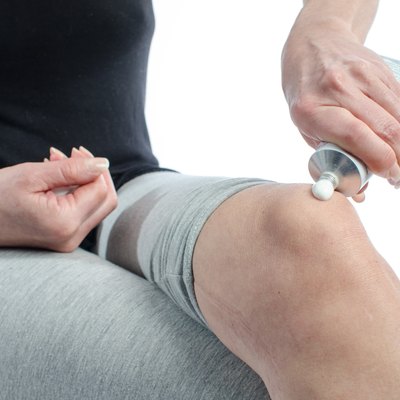 Woman putting cream on her knee