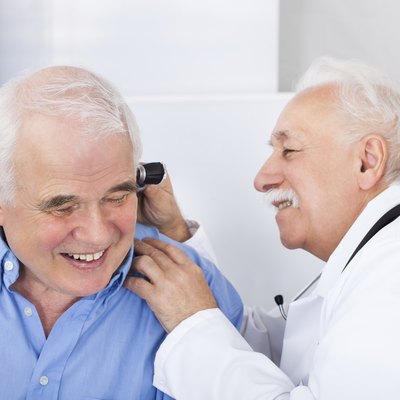 Doctor Examining Senior Man's Ear With Otoscope