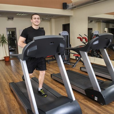young man running at treadmill in gym