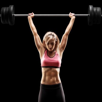 Muscular woman lifting a heavy barbell on black background