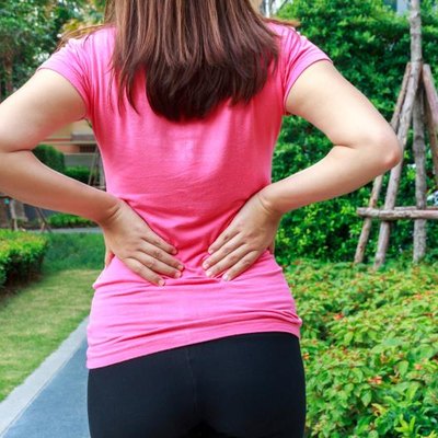 Female athlete lower back painful injury. Sporty woman backache and injury.