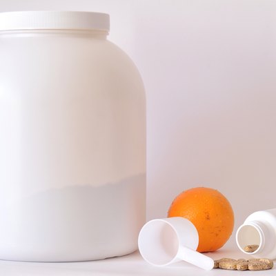 Big jar of protein powder, bottle of pills, orange