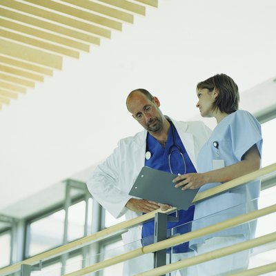 Mature male doctor and young female nurse holding folder by railing