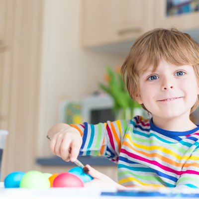 Little kid boy coloring eggs for Easter holiday