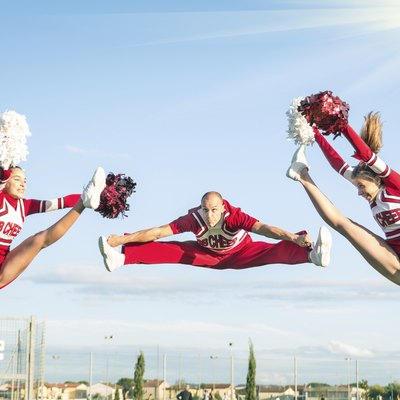 Cheerleaders team performing a Jump with male Coach