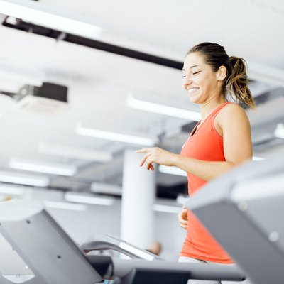 Beautiful young woman running on a treadmill in gym