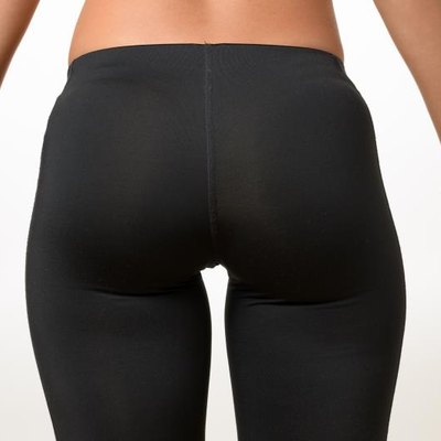 Toned buttocks and thighs of a shapely young woman holding her hands away from her sides isolated on white, close up view