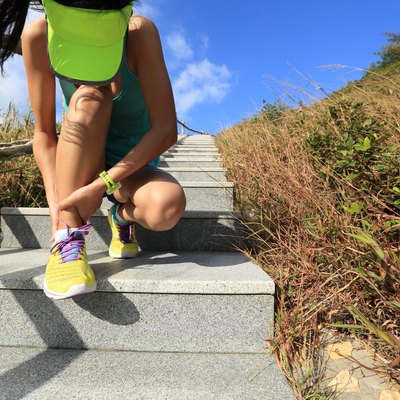 young woman runner hold her sports injured ankle